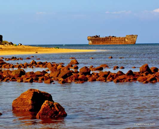 The hull of a rusty Navy ship sticking out of the water can be seen from Shipwreck Beach on Lanai.