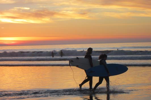 Surfers at sunset, La Jolla Shores Beach, San Diego, California.
